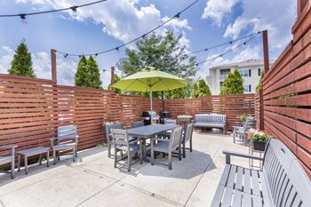 A patio with a table and chairs under a yellow umbrella.